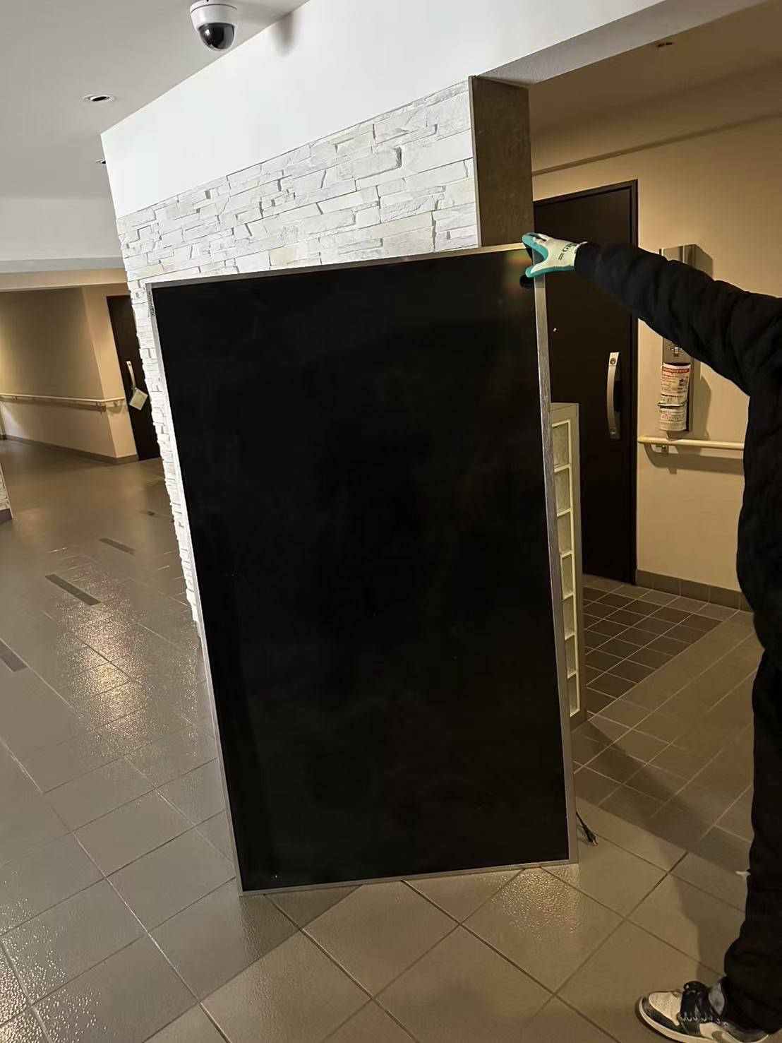 スタッフが大型テレビを搬出する様子